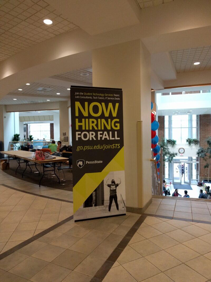 Tall Student Technology Services Now Hiring for Fall banner at top of stairs